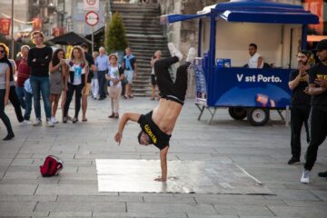 man wearing black and yellow printed crew-neck t-shirt doing stunts a and people watching him